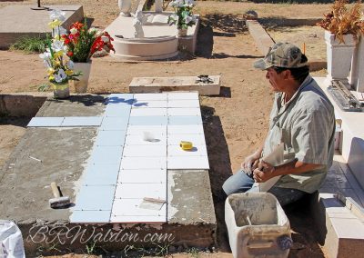 An albañil lays tile to decorate a grave on the Dia de Muertos